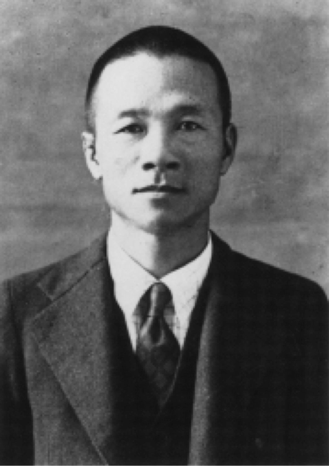 Black and white portrait of a man in formal attire against a plain background
